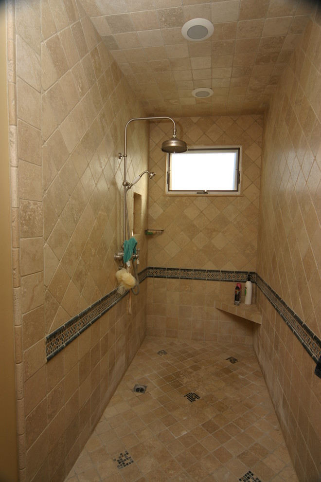 This is an example of a mid-sized mediterranean 3/4 bathroom in Orange County with raised-panel cabinets, medium wood cabinets, a drop-in tub, an open shower, beige tile, multi-coloured tile, mosaic tile, beige walls, travertine floors, an undermount sink and marble benchtops.