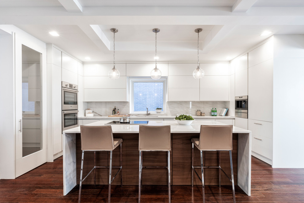 Contemporary u-shaped kitchen in New York with flat-panel cabinets, white cabinets, stainless steel appliances, dark hardwood floors, with island, brown floor and white benchtop.