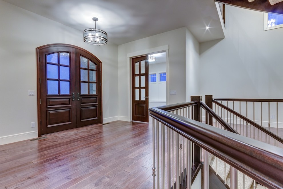 Example of a transitional medium tone wood floor eat-in kitchen design in Calgary with a double-bowl sink, raised-panel cabinets, dark wood cabinets, granite countertops, gray backsplash, glass tile backsplash, stainless steel appliances and an island