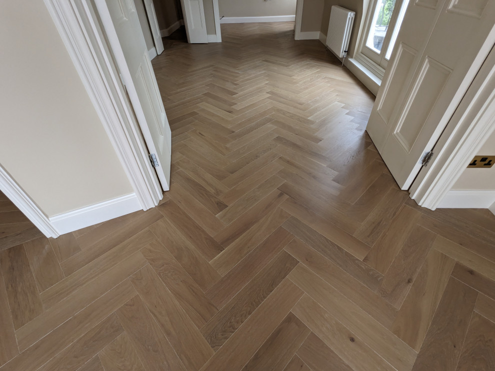 Expansive traditional hallway in London with light hardwood floors.