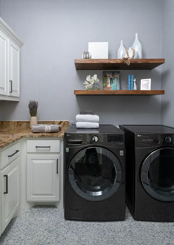 Small transitional l-shaped dedicated laundry room in Dallas with grey walls, a side-by-side washer and dryer, multi-coloured floor and brown benchtop.