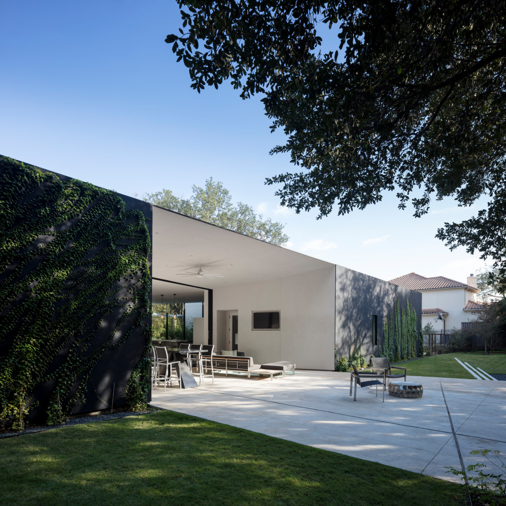 На фото: большой двор на переднем дворе в стиле модернизм с летней кухней, покрытием из бетонных плит и навесом