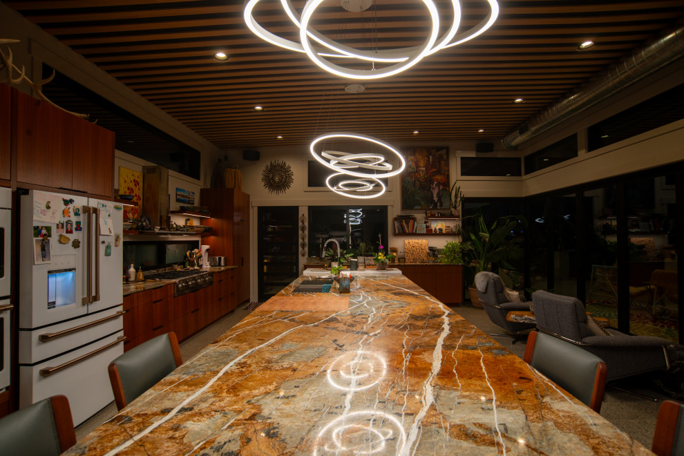Example of a mid-sized minimalist concrete floor, gray floor and wood ceiling open concept kitchen design in Seattle with a double-bowl sink, flat-panel cabinets, medium tone wood cabinets, quartzite countertops, white appliances, an island and multicolored countertops