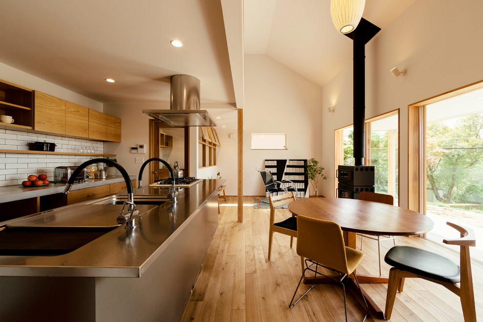 Photo of an asian open plan dining in Other with white walls, light hardwood floors, a wood stove and brown floor.