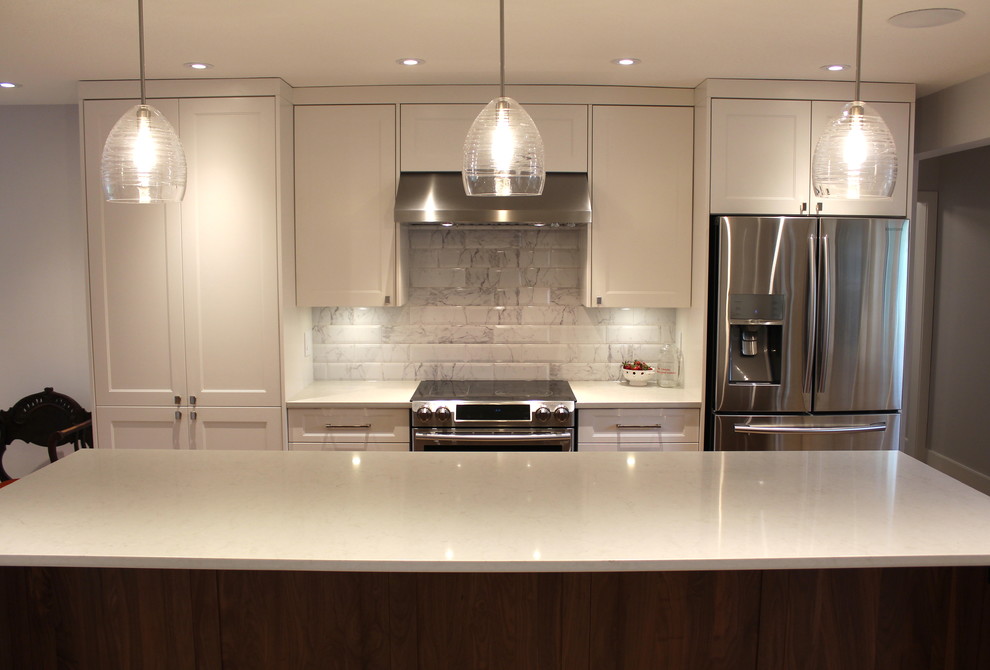 Large transitional l-shaped light wood floor eat-in kitchen photo with an undermount sink, shaker cabinets, white cabinets, quartz countertops, white backsplash, ceramic backsplash, stainless steel appliances and an island
