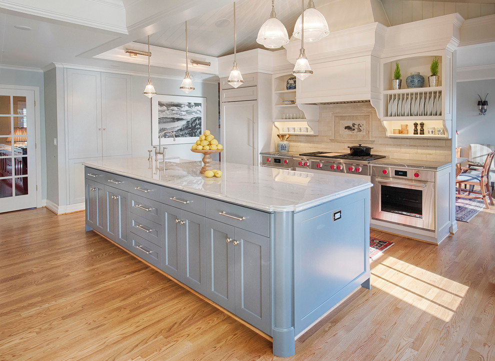 Photo of a large traditional eat-in kitchen in Portland with a farmhouse sink, shaker cabinets, grey cabinets, grey splashback, panelled appliances, light hardwood floors and with island.