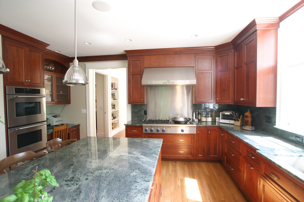 Photo of a large traditional l-shaped separate kitchen in New York with an undermount sink, recessed-panel cabinets, dark wood cabinets, granite benchtops, blue splashback, stone slab splashback, stainless steel appliances, medium hardwood floors, with island, brown floor and blue benchtop.