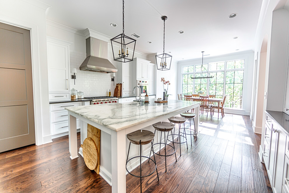 Mid-sized transitional galley medium tone wood floor and brown floor enclosed kitchen photo in Birmingham with an undermount sink, beaded inset cabinets, white cabinets, marble countertops, white backsplash, cement tile backsplash, stainless steel appliances and an island