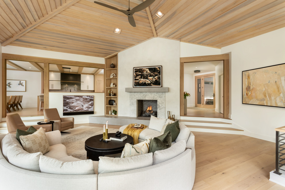 Ejemplo de salón abierto tradicional renovado grande con paredes blancas, suelo de madera clara, marco de chimenea de yeso, suelo beige y madera