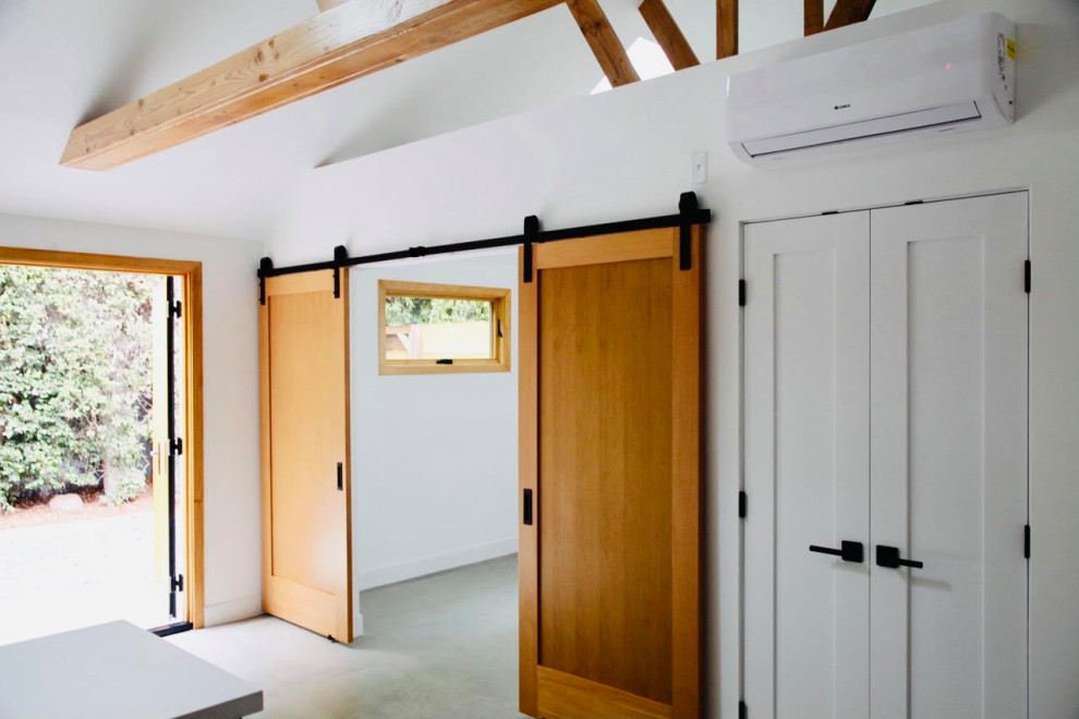 Пример оригинального дизайна: большое фойе в стиле неоклассика (современная классика) с белыми стенами, бетонным полом, двустворчатой входной дверью, входной дверью из дерева среднего тона, серым полом и балками на потолке