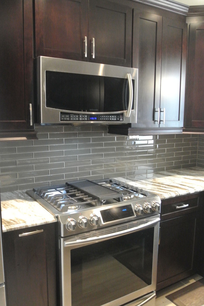 Inspiration for a mid-sized transitional u-shaped eat-in kitchen remodel in Toronto with an undermount sink, shaker cabinets, dark wood cabinets, quartzite countertops, stainless steel appliances and an island