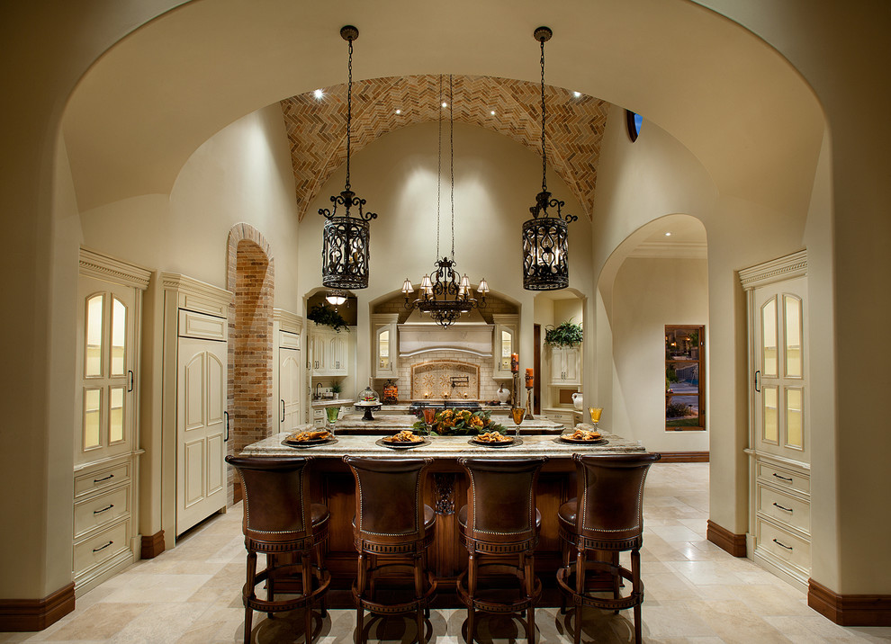Inspiration for an expansive mediterranean single-wall open plan kitchen in Phoenix with a farmhouse sink, raised-panel cabinets, medium wood cabinets, granite benchtops, beige splashback, subway tile splashback, stainless steel appliances, travertine floors and multiple islands.