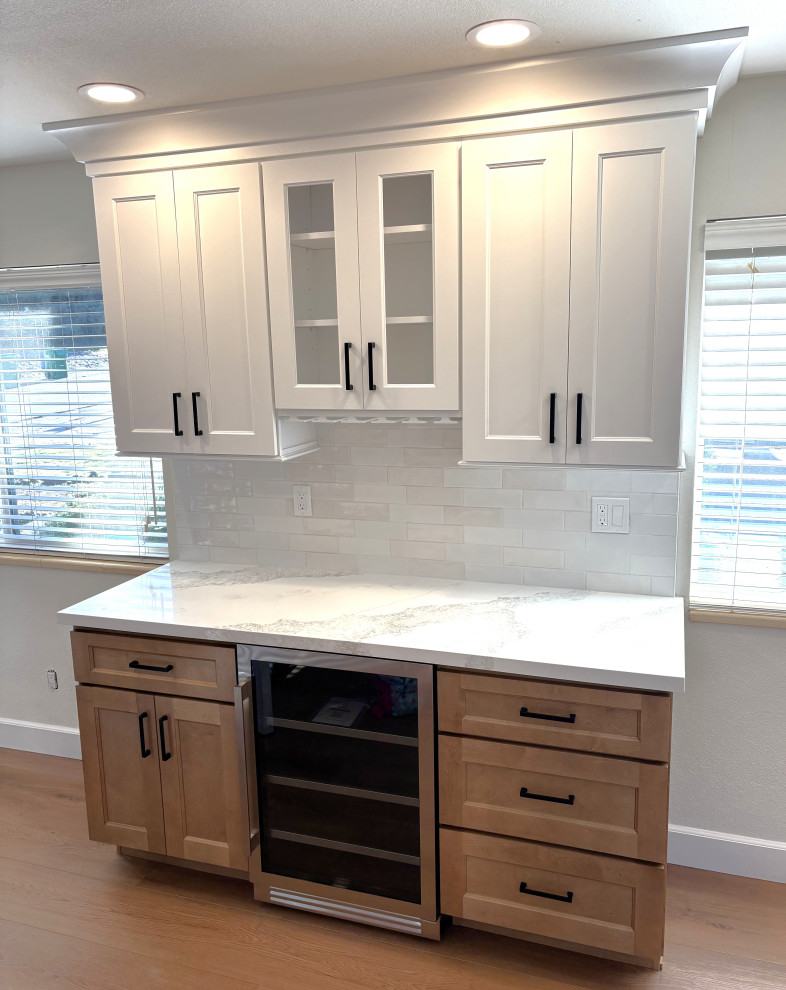 Open concept kitchen - large transitional l-shaped vinyl floor and brown floor open concept kitchen idea with a farmhouse sink, shaker cabinets, white cabinets, quartz countertops, white backsplash, ceramic backsplash, stainless steel appliances, an island and multicolored countertops