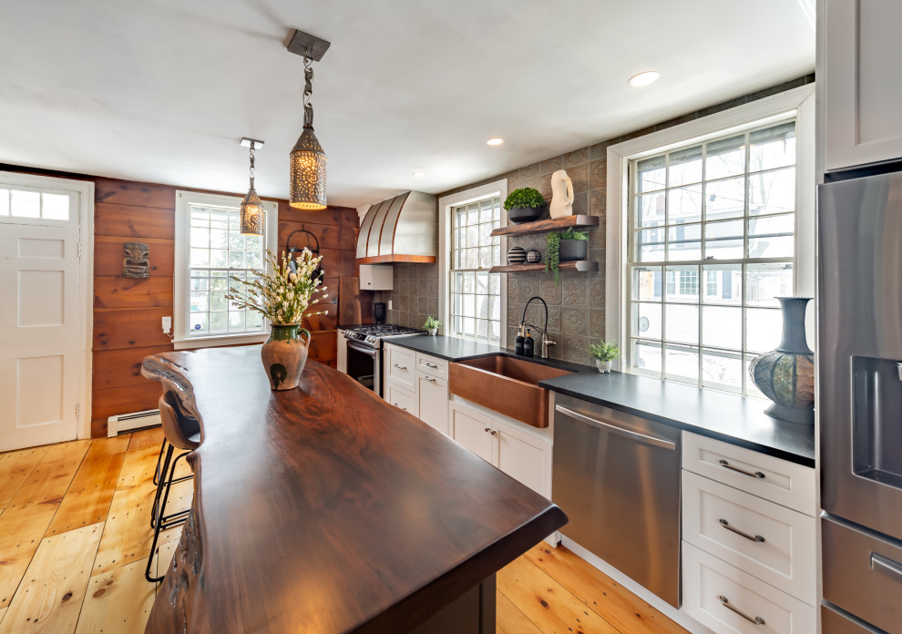 Design ideas for a mid-sized traditional galley kitchen in Boston with white cabinets, wood benchtops, metallic splashback, metal splashback, stainless steel appliances, brown benchtop, a farmhouse sink, shaker cabinets, medium hardwood floors, with island and brown floor.