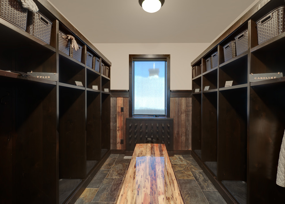 Mudroom - large rustic slate floor and multicolored floor mudroom idea with beige walls and a dark wood front door
