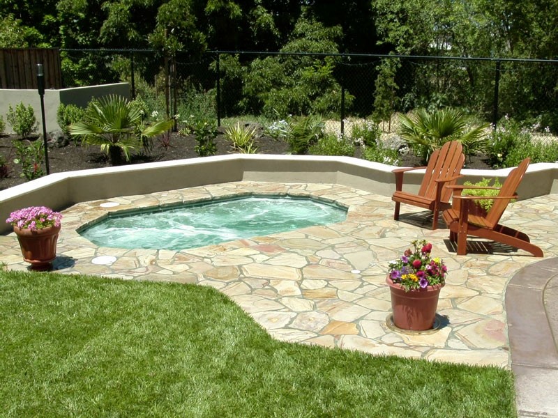 Backyard stone and custom-shaped hot tub photo