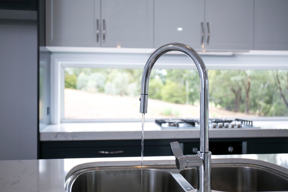 Inspiration for a mid-sized traditional galley kitchen pantry with an undermount sink, shaker cabinets, blue cabinets, quartz benchtops, metallic splashback, window splashback, stainless steel appliances, linoleum floors, with island, grey floor and white benchtop.