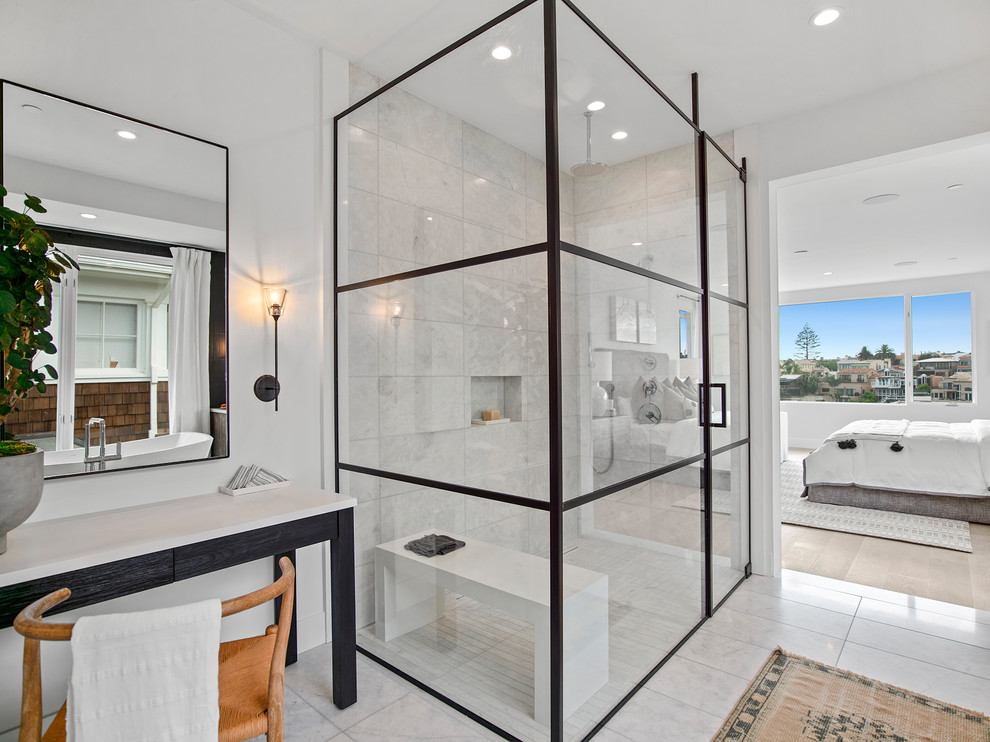 This is an example of a large contemporary master bathroom in Orange County with furniture-like cabinets, dark wood cabinets, a freestanding tub, an alcove shower, white tile, marble, white walls, marble floors, an undermount sink, marble benchtops, white floor, a hinged shower door and white benchtops.