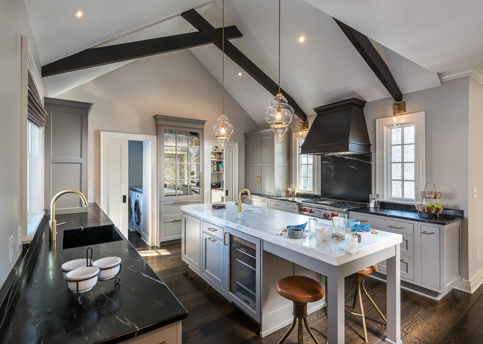 Inspiration for a large transitional dark wood floor and brown floor kitchen remodel with a farmhouse sink, recessed-panel cabinets, gray cabinets, soapstone countertops, stainless steel appliances and an island
