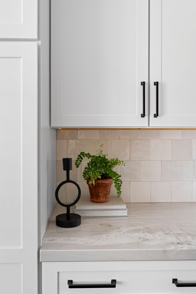 Transitional vinyl floor and brown floor kitchen photo with a farmhouse sink, shaker cabinets, white cabinets, quartzite countertops, white backsplash and stainless steel appliances