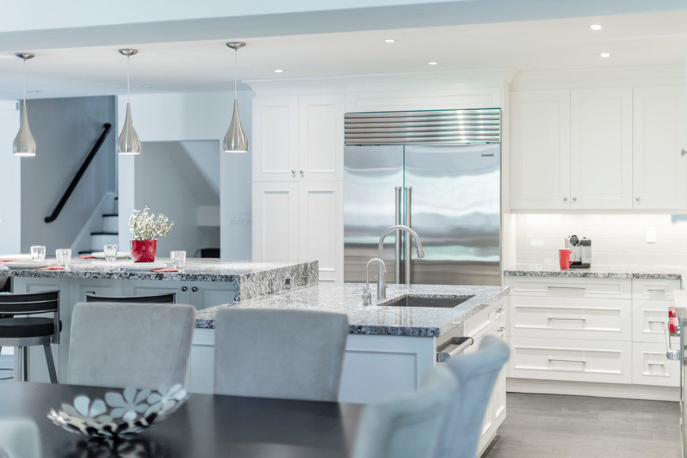 Example of a mid-sized transitional brown floor kitchen design in Toronto with white cabinets, stainless steel appliances and an island