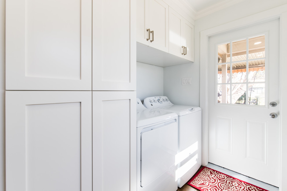 Photo of a small arts and crafts single-wall utility room in Dallas with shaker cabinets, white cabinets, white walls, light hardwood floors and a side-by-side washer and dryer.