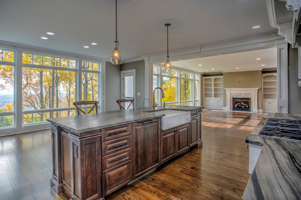 Expansive transitional l-shaped open plan kitchen in New York with a farmhouse sink, raised-panel cabinets, beige cabinets, soapstone benchtops, beige splashback, porcelain splashback, panelled appliances, dark hardwood floors and with island.