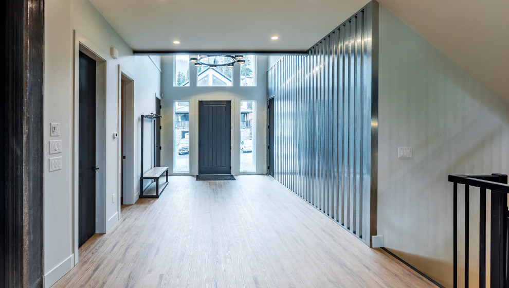 Inspiration for a large modern foyer in Vancouver with metallic walls, vinyl floors, a single front door, a black front door and brown floor.