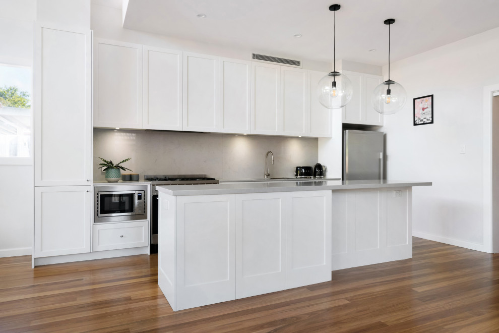 Inspiration for a mid-sized transitional open plan kitchen in Sydney with an undermount sink, shaker cabinets, white cabinets, quartz benchtops, grey splashback, engineered quartz splashback, stainless steel appliances, with island and grey benchtop.