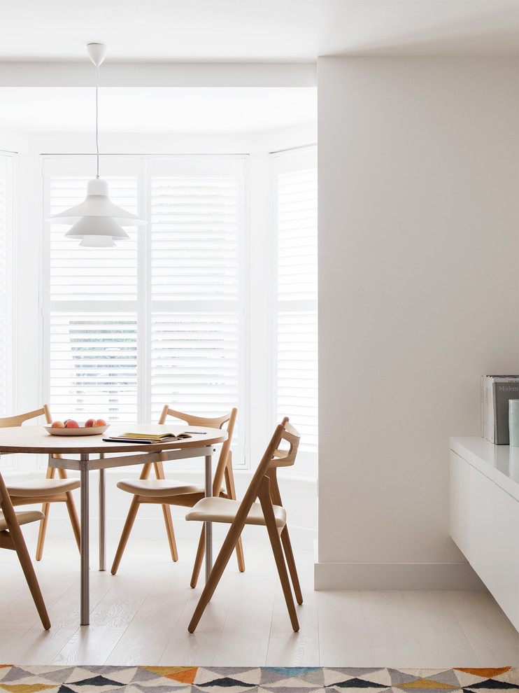 Photo of a scandinavian dining room in London with white walls.