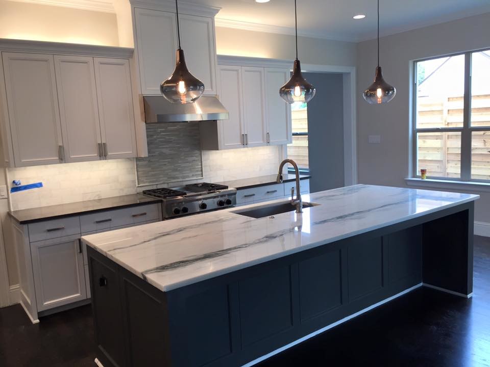 Mid-sized transitional single-wall dark wood floor open concept kitchen photo in Dallas with recessed-panel cabinets, white cabinets, marble countertops, white backsplash, stone tile backsplash, stainless steel appliances and an island