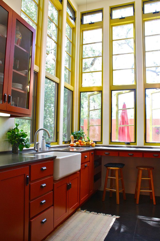 Photo of a kitchen in Santa Barbara with glass-front cabinets, a farmhouse sink and orange cabinets.