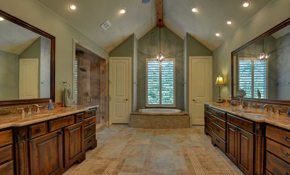 Photo of a large traditional master bathroom in Dallas with an undermount sink, raised-panel cabinets, dark wood cabinets, granite benchtops, a drop-in tub, a double shower, a one-piece toilet, beige tile, porcelain tile, porcelain floors and green walls.