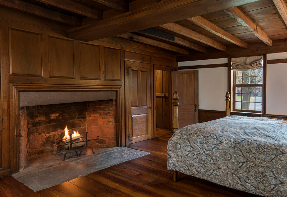 Foto de dormitorio principal campestre grande con suelo de madera en tonos medios, todas las chimeneas y vigas vistas