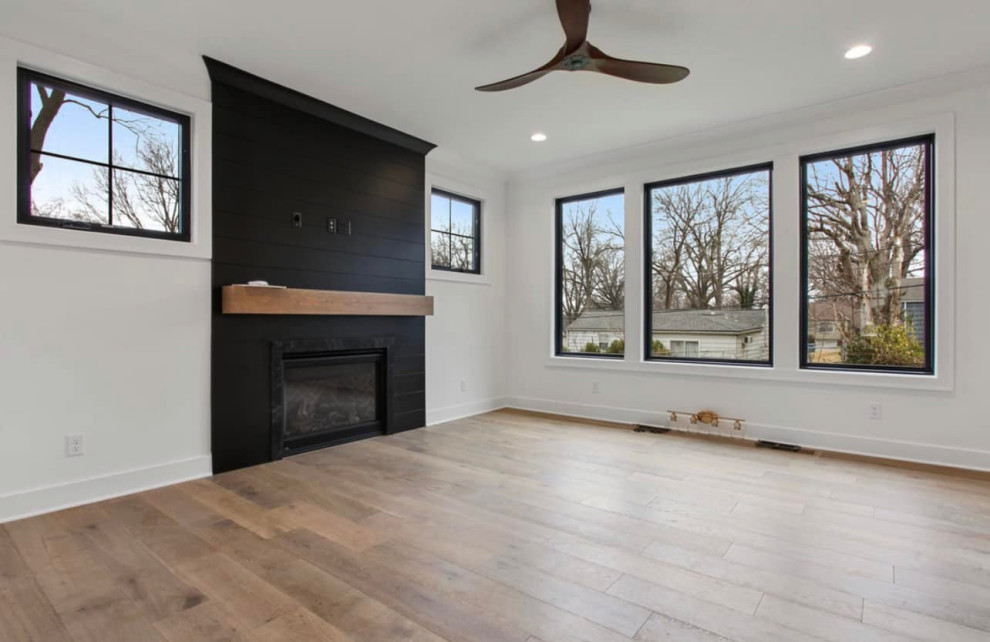 This is an example of a mid-sized contemporary formal open concept living room in Chicago with white walls, light hardwood floors, a standard fireplace, a wall-mounted tv and beige floor.