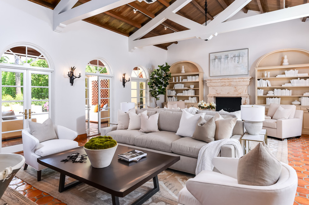 Photo of a mediterranean family room in Miami with a library, white walls, terra-cotta floors, a standard fireplace, a stone fireplace surround and orange floor.
