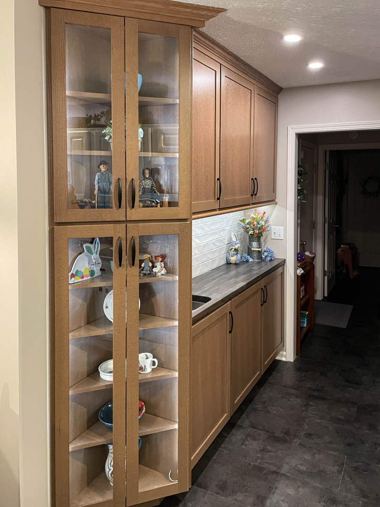 This is an example of a small transitional single-wall home bar in Cleveland with an undermount sink, flat-panel cabinets, light wood cabinets, wood benchtops, white splashback, ceramic splashback and brown benchtop.