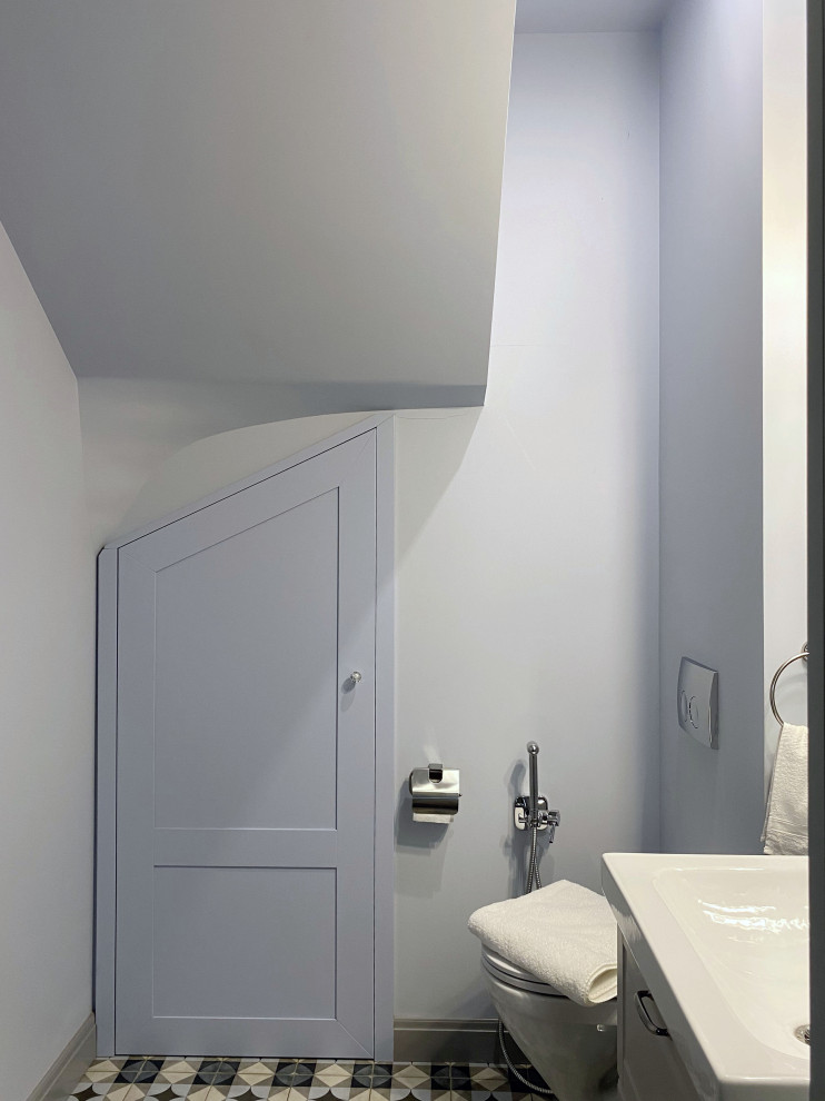 Exemple d'un WC suspendu chic de taille moyenne avec un placard avec porte à panneau encastré, des portes de placard grises, un carrelage bleu, un carrelage métro, un mur bleu, un sol en carrelage de porcelaine, un lavabo posé, un sol multicolore et meuble-lavabo suspendu.