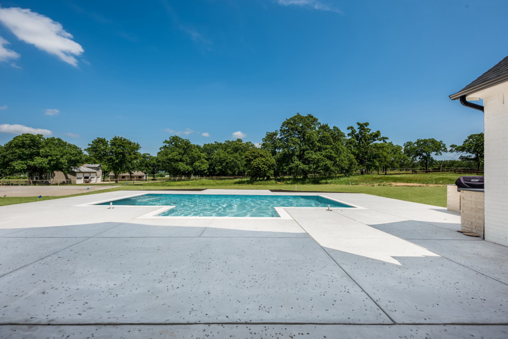 Foto di una grande piscina monocorsia country rettangolare dietro casa con paesaggistica bordo piscina e cemento stampato
