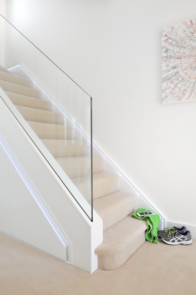 This is an example of a large contemporary carpeted u-shaped staircase in Cardiff with glass risers and glass railing.