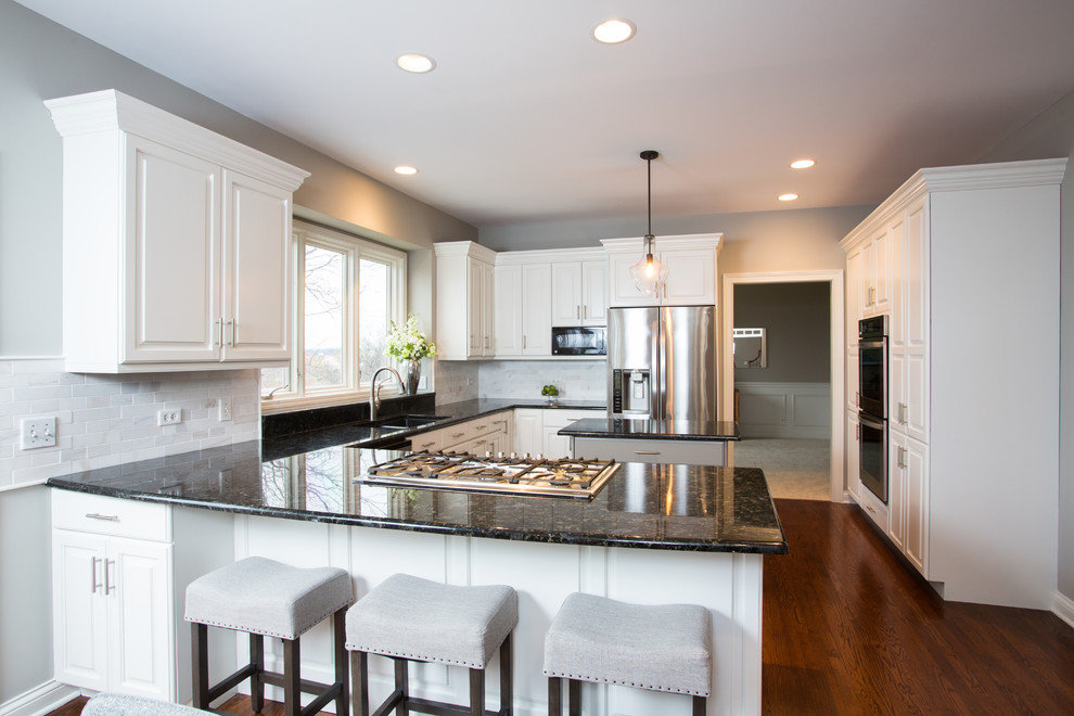 Large transitional u-shaped medium tone wood floor and brown floor eat-in kitchen photo in Chicago with a double-bowl sink, raised-panel cabinets, white cabinets, granite countertops, white backsplash, ceramic backsplash, stainless steel appliances and an island