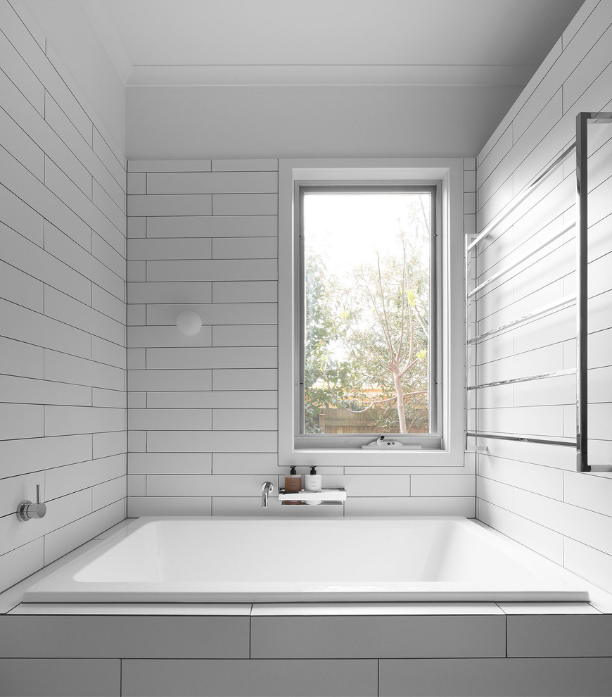Contemporary bathroom in Melbourne with a drop-in tub, white tile and white walls.