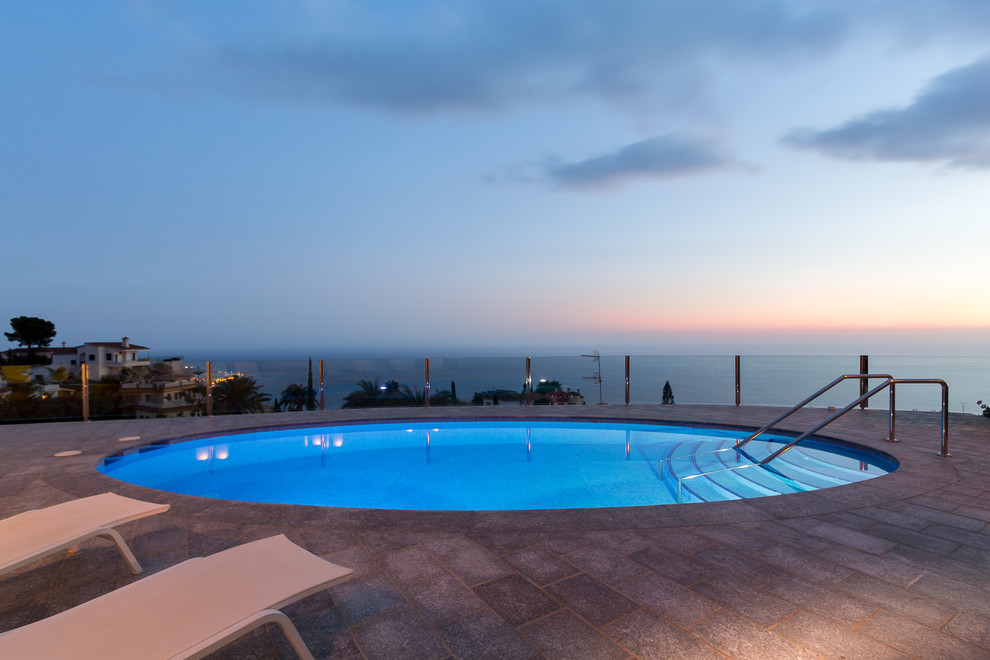Photo of a large contemporary rooftop round lap pool in Other with brick pavers.