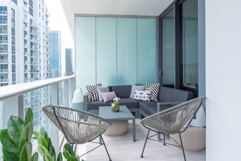 Contemporary balcony in Miami with a roof extension and glass railing for for apartments.