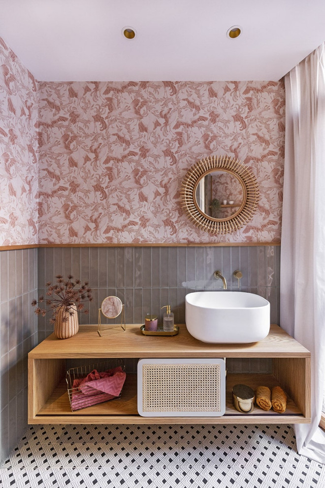 Imagen de cuarto de baño único y flotante actual con armarios abiertos, puertas de armario de madera oscura, baldosas y/o azulejos grises, paredes rosas, lavabo sobreencimera, suelo multicolor, encimeras marrones y papel pintado