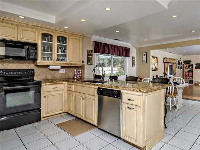 Example of a large transitional u-shaped ceramic tile open concept kitchen design in Denver with an undermount sink, raised-panel cabinets, beige cabinets, granite countertops, beige backsplash, terra-cotta backsplash and black appliances