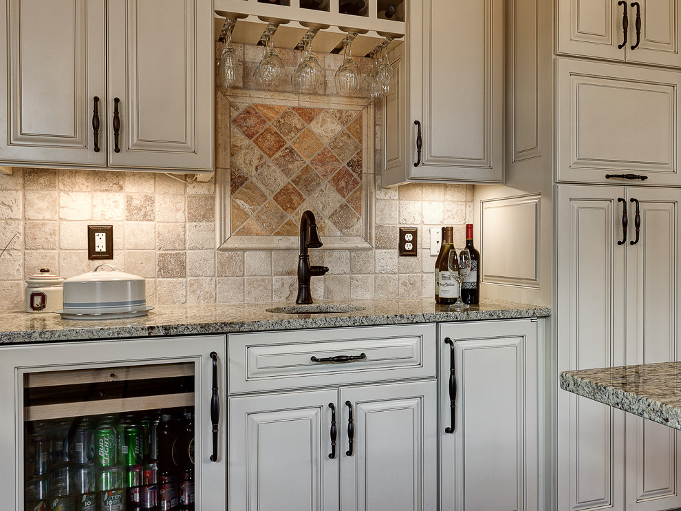 Mountain style enclosed kitchen photo in Columbus with a farmhouse sink, flat-panel cabinets, white cabinets, marble countertops, beige backsplash, stone tile backsplash and stainless steel appliances