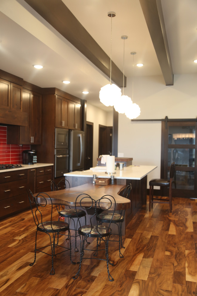 Example of a mid-sized transitional galley medium tone wood floor eat-in kitchen design with a double-bowl sink, recessed-panel cabinets, dark wood cabinets, granite countertops, red backsplash, porcelain backsplash, stainless steel appliances and an island