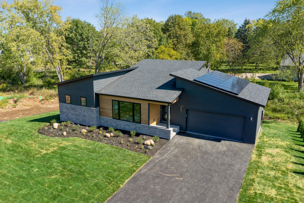 Photo of a mid-sized modern two-storey black house exterior in Minneapolis with concrete fiberboard siding, a butterfly roof, a shingle roof, a black roof and clapboard siding.