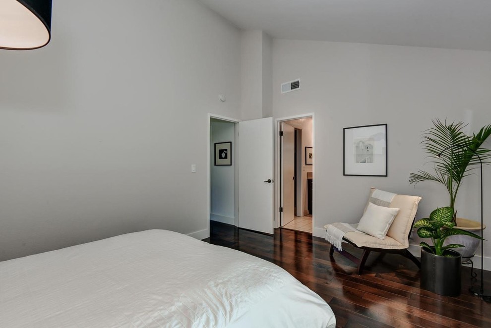 This is an example of a mid-sized modern master bedroom in San Francisco with white walls, dark hardwood floors and brown floor.